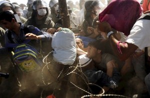 Migrants fall as they rush to cross into Macedonia after Macedonian police allowed a small group of people to pass through a passageway, as they try to regulate the flow of migrants at the Macedonian-Greek border September 2, 2015. Up to 3,000 migrants are expected to cross into Macedonia every day in the coming months, most of them refugees fleeing war, particularly from Syria, the United Nations said last week. REUTERS/Ognen Teofilovski TPX IMAGES OF THE DAY - RTX1QR2L